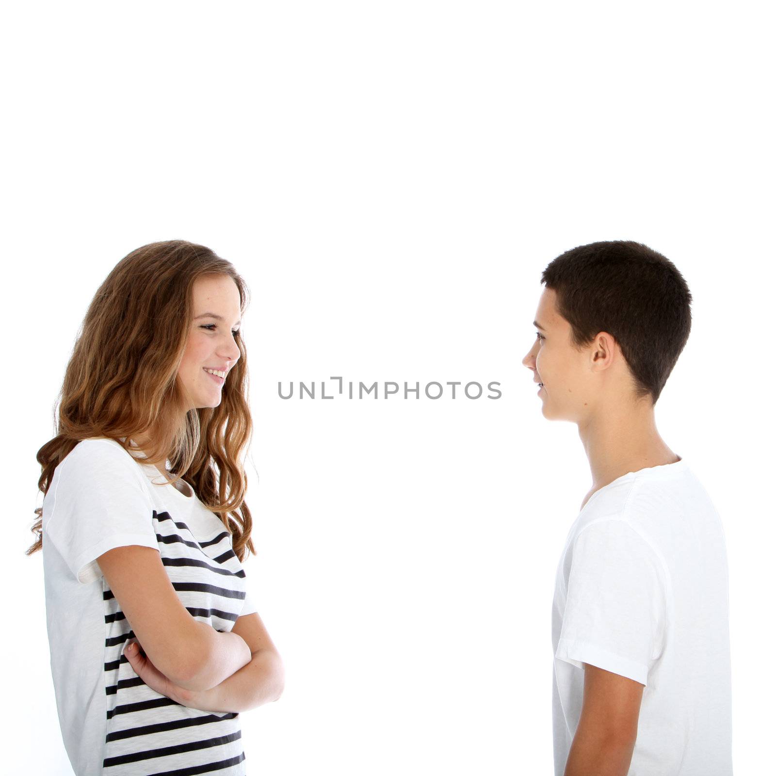 Attractive young teenage boy and girl standing sideways facing each other chatting isolated on white