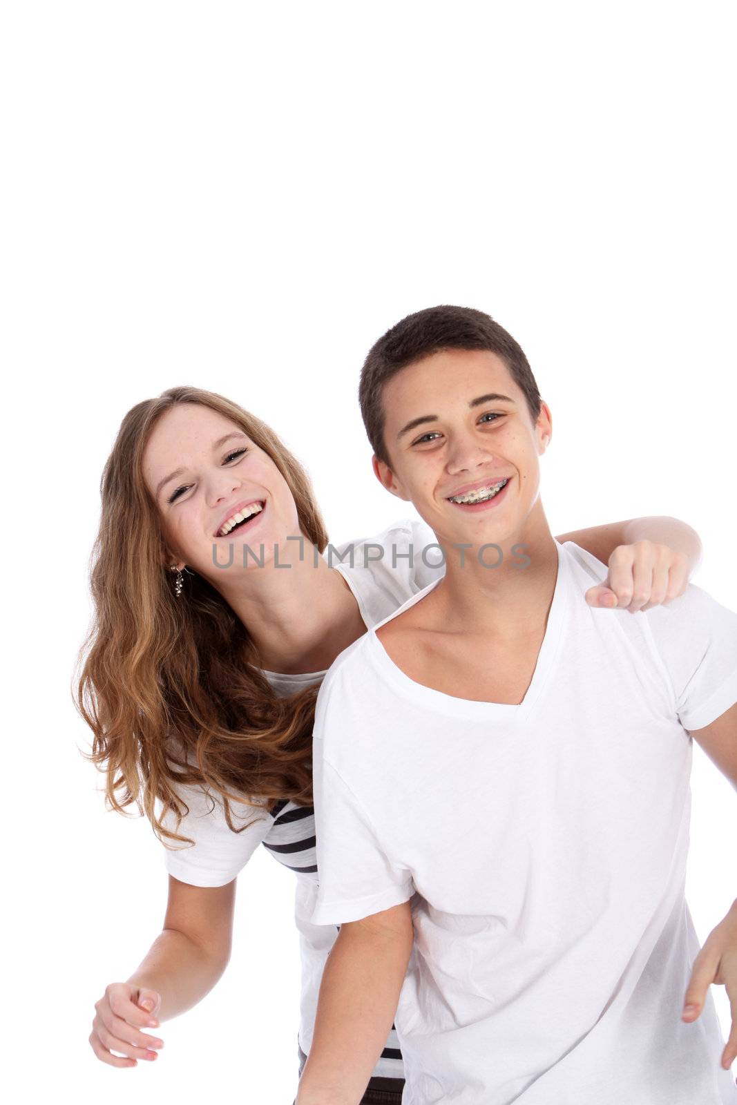 Laughing young teenagers having fun together with the girl draping her arm over the boy's shoulder from behind with copyspace isolated on white