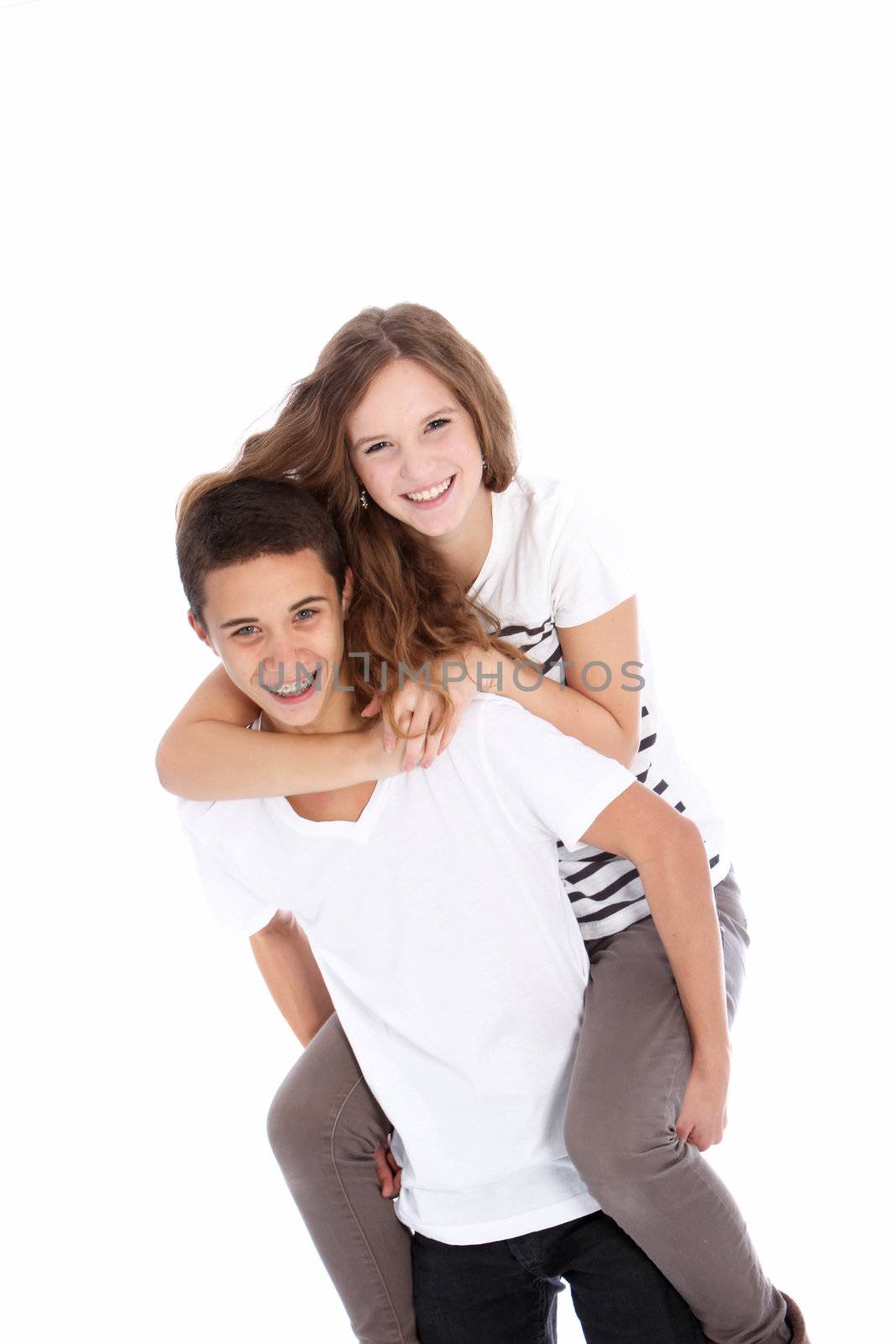Happy teenagers riding piggyback with the laughing girl astride the boys back isolated on white