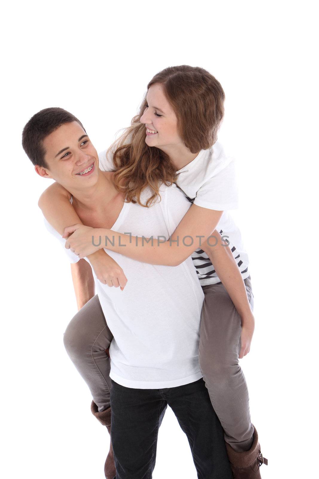 Young attractive teenage boy giving his laughing girlfriend a piggyback ride as they enjoy some fun time together isolated on white