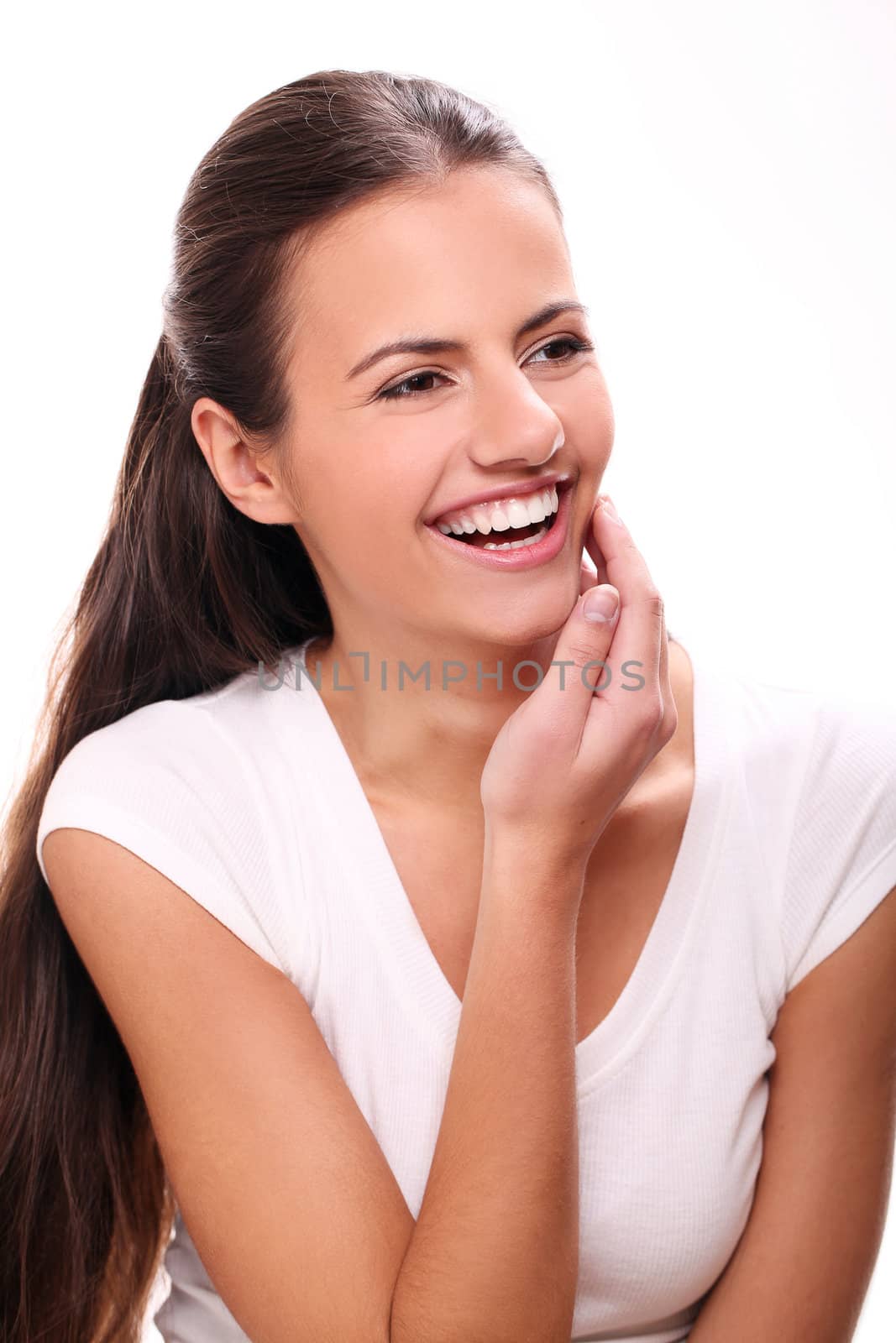 Cute and young smiling woman with white teeth touching her face