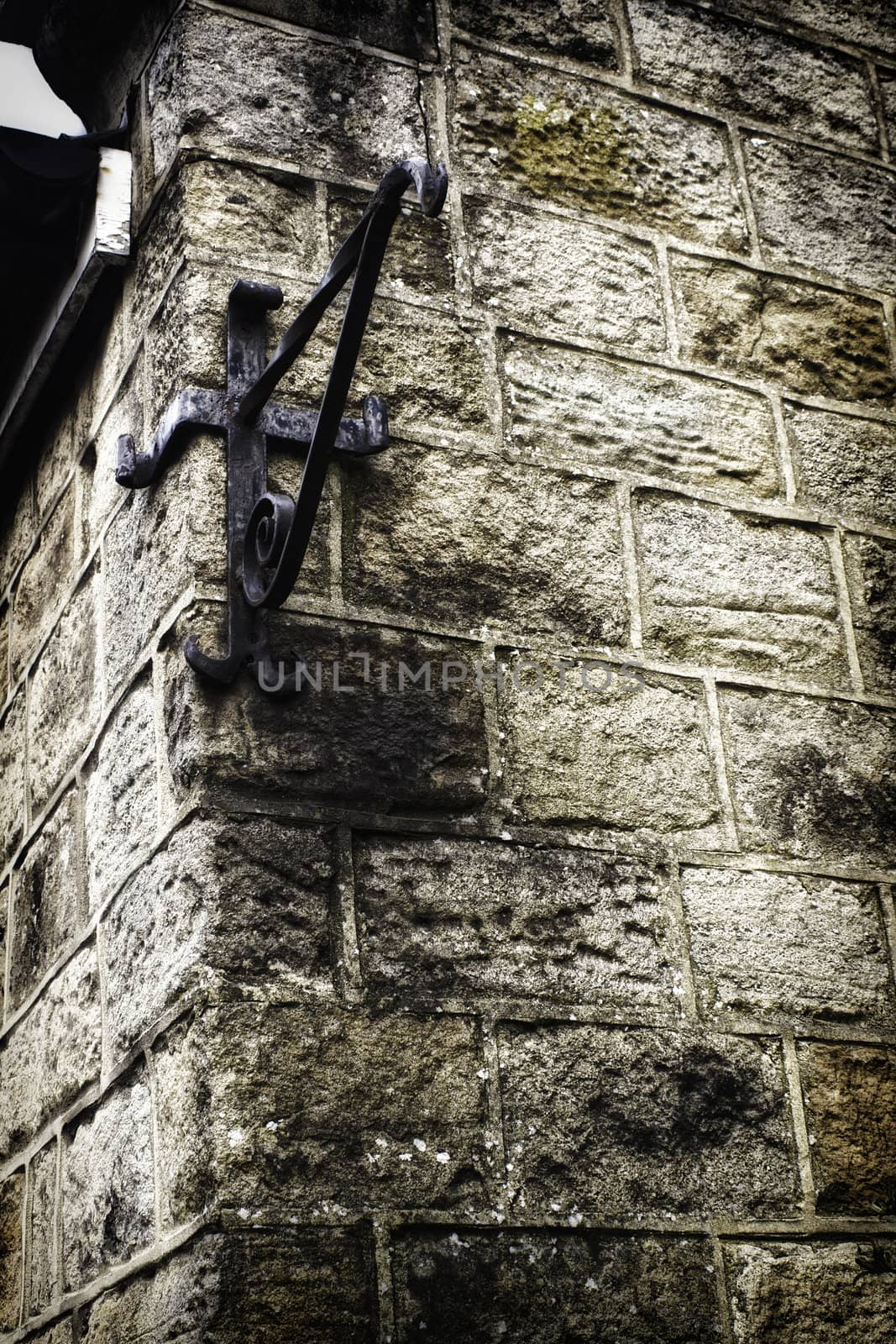 Empty metal angle bracket on the corner of an old grungy stone wall used to mount a sign