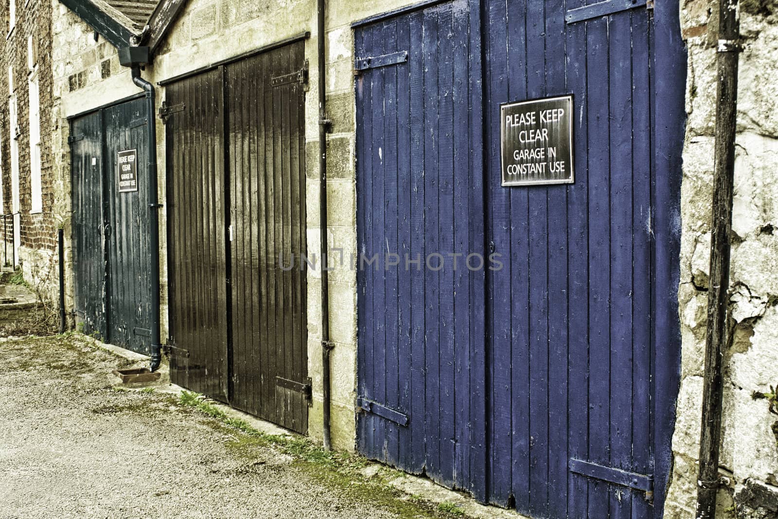 Row of grungy painted garage doors in an urban environmnet with a Please keep clear sign on one