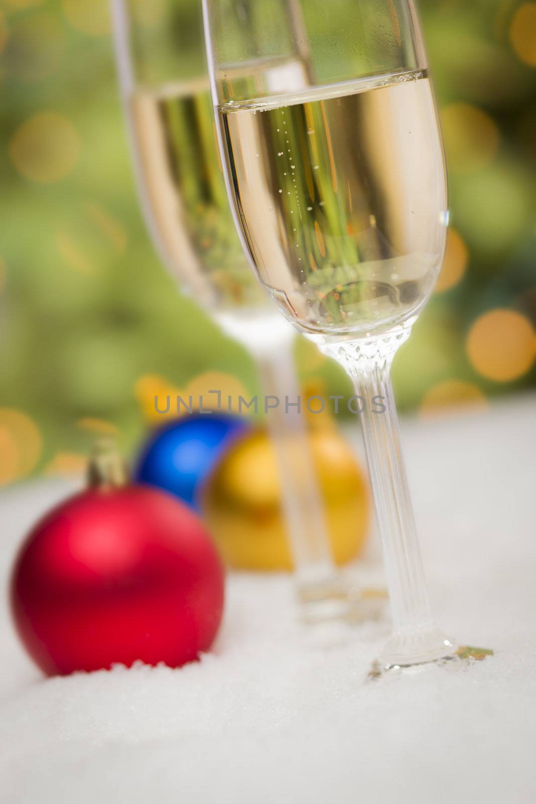 Beautiful Various Colored Christmas Ornaments and Champagne Glasses on Snow Flakes In Front of an Abstract Background.