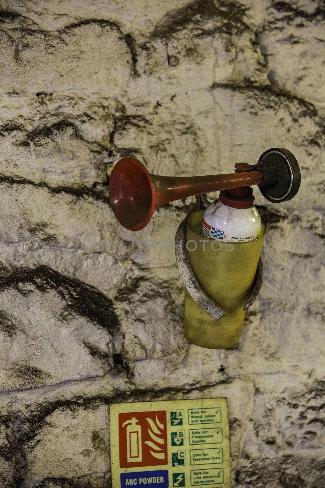 Fire extinguisher and large trumpet shaped nozzle mounted on an old stone wall