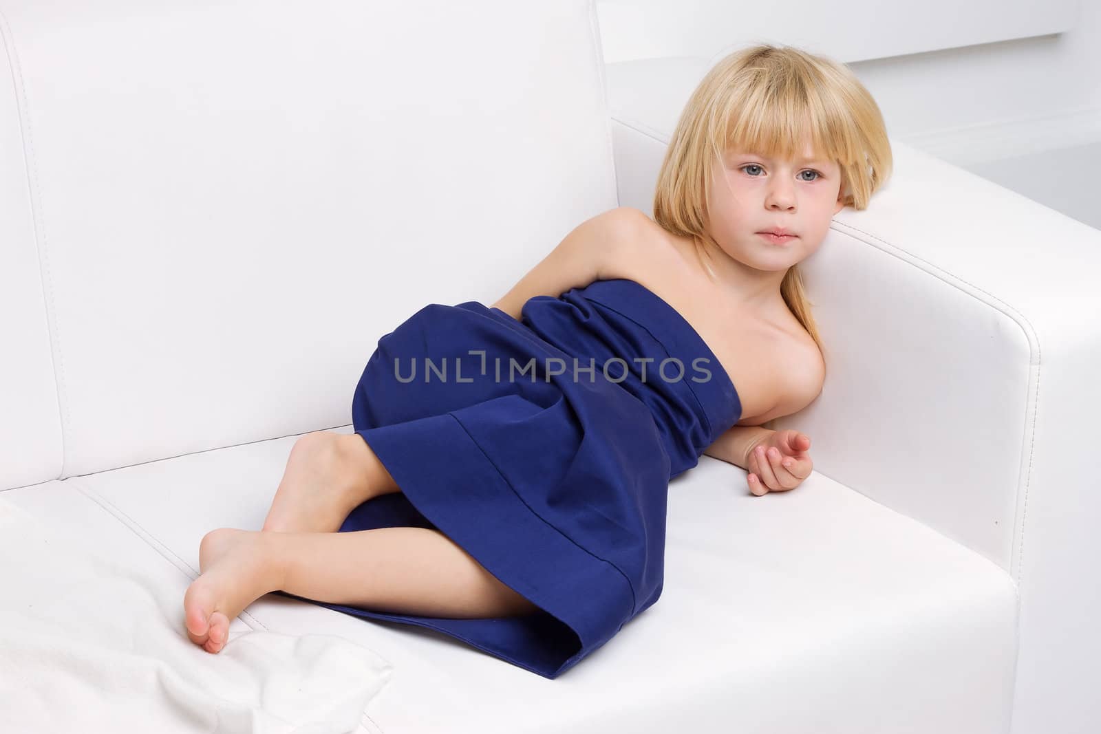 3 years old girl is in a blue dress on a white sofa