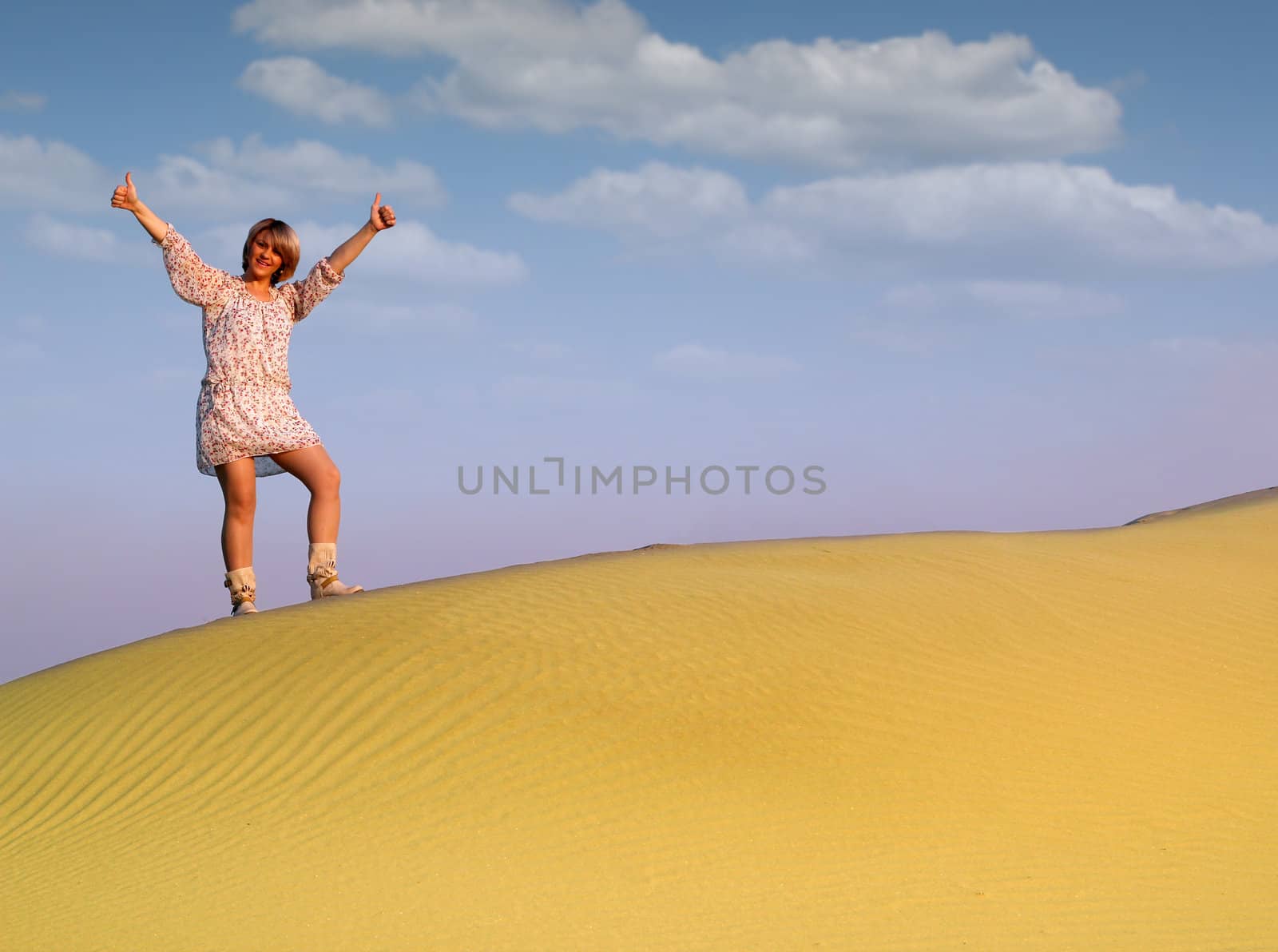 beautiful woman with thumbs up standing on desert dune