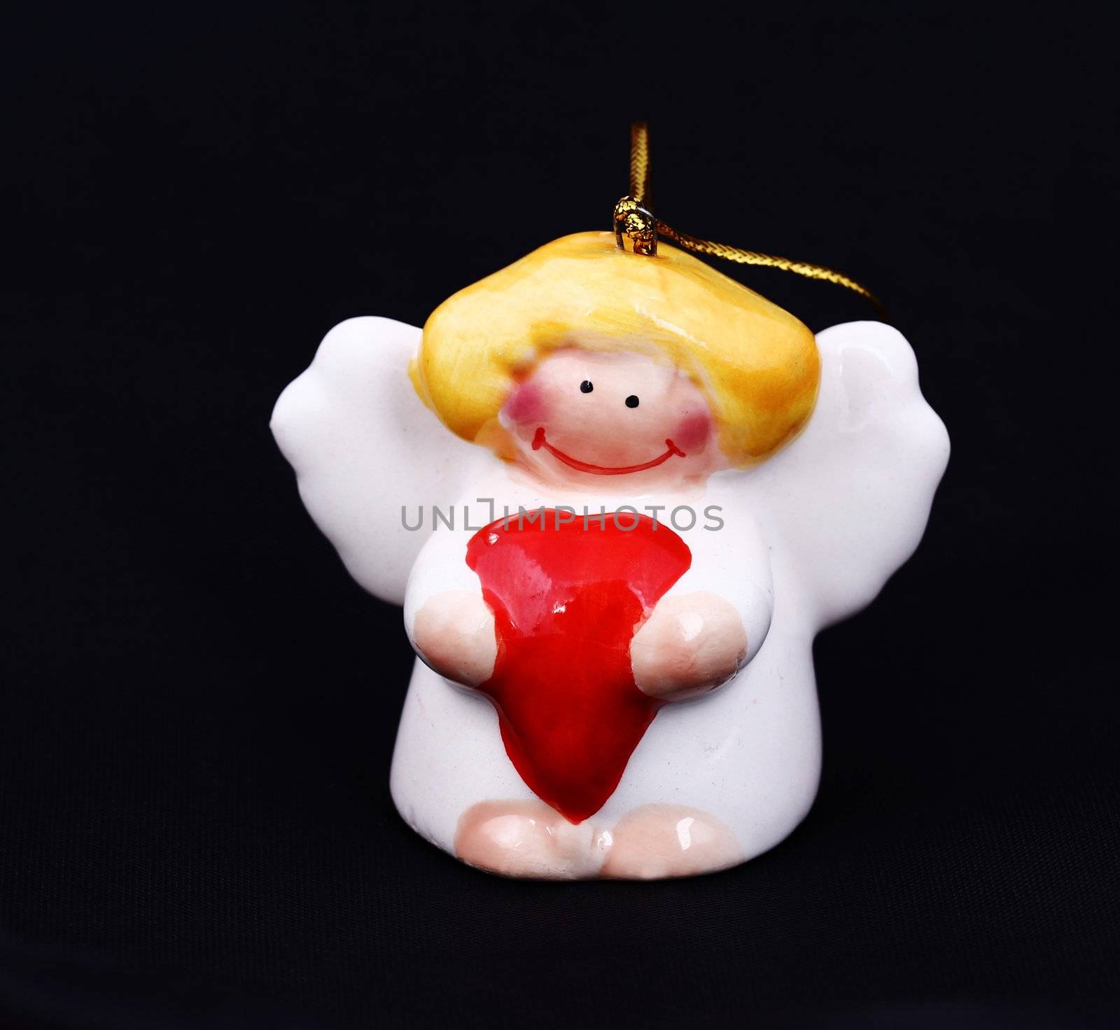 Cute Christmas angel with red heart hanging against black background