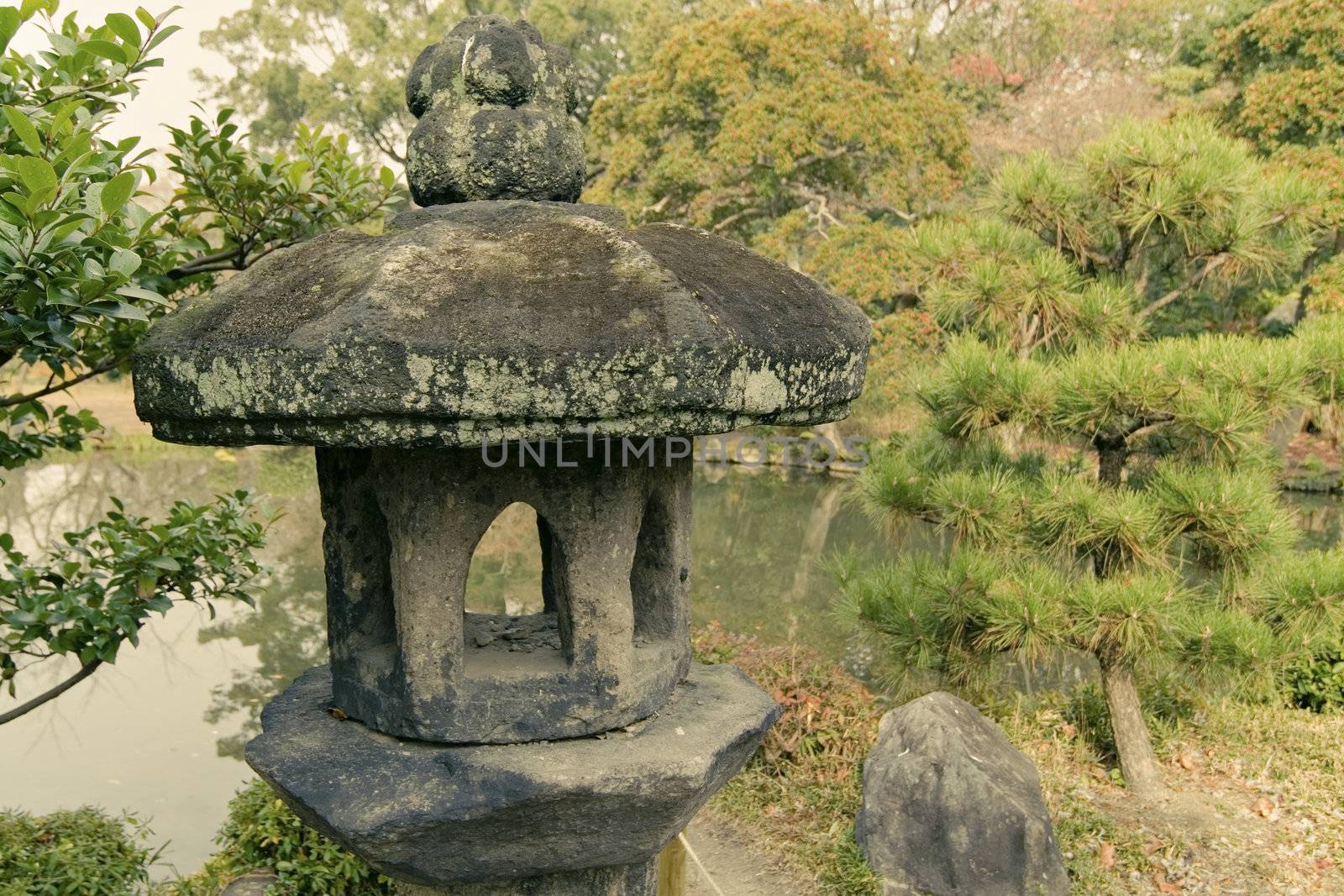 ancient stone lantern in traditional Japanese zen garden in Kyoto, Japan; focus on lantern