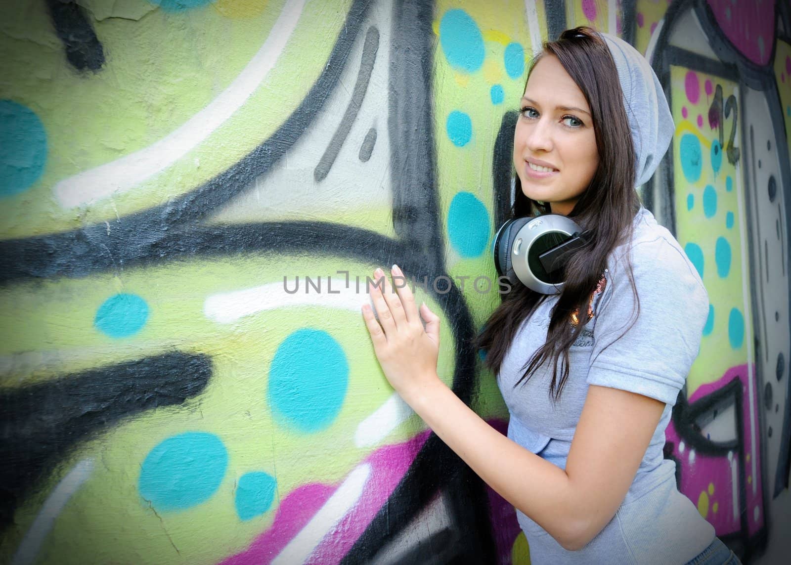 Girl holding spray against graffiti wall