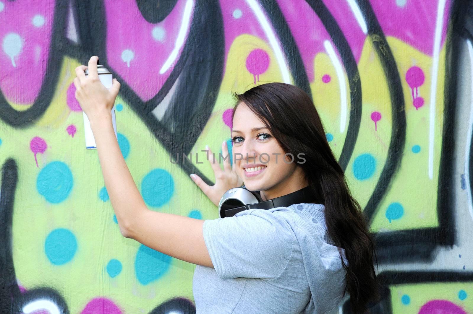 Young and beautiful girl posing against wall with graffiti