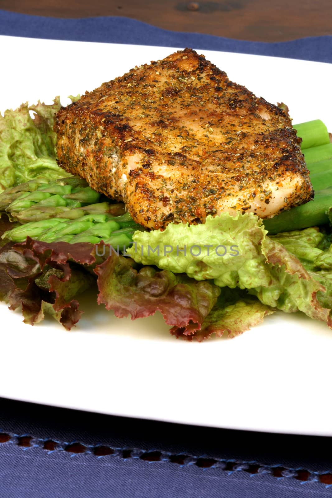 delicious grilled sea bass, seasoned with fine spices with asparagus and lettuce bed 