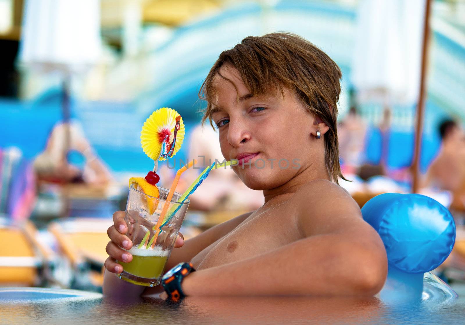 Boy with wet hair, drinking a cocktail by the  swimming pool.