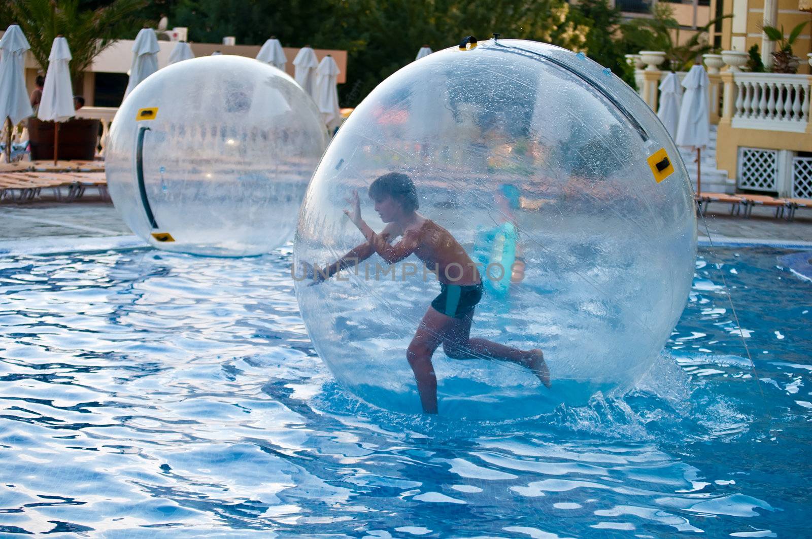 Boy in the air ball in the water in the pool.