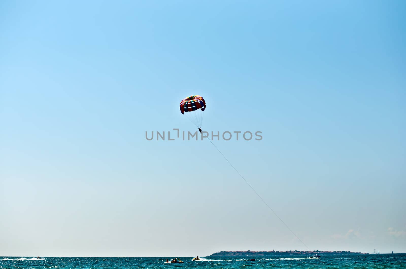 Colorful hang glider in sky over blue sea .