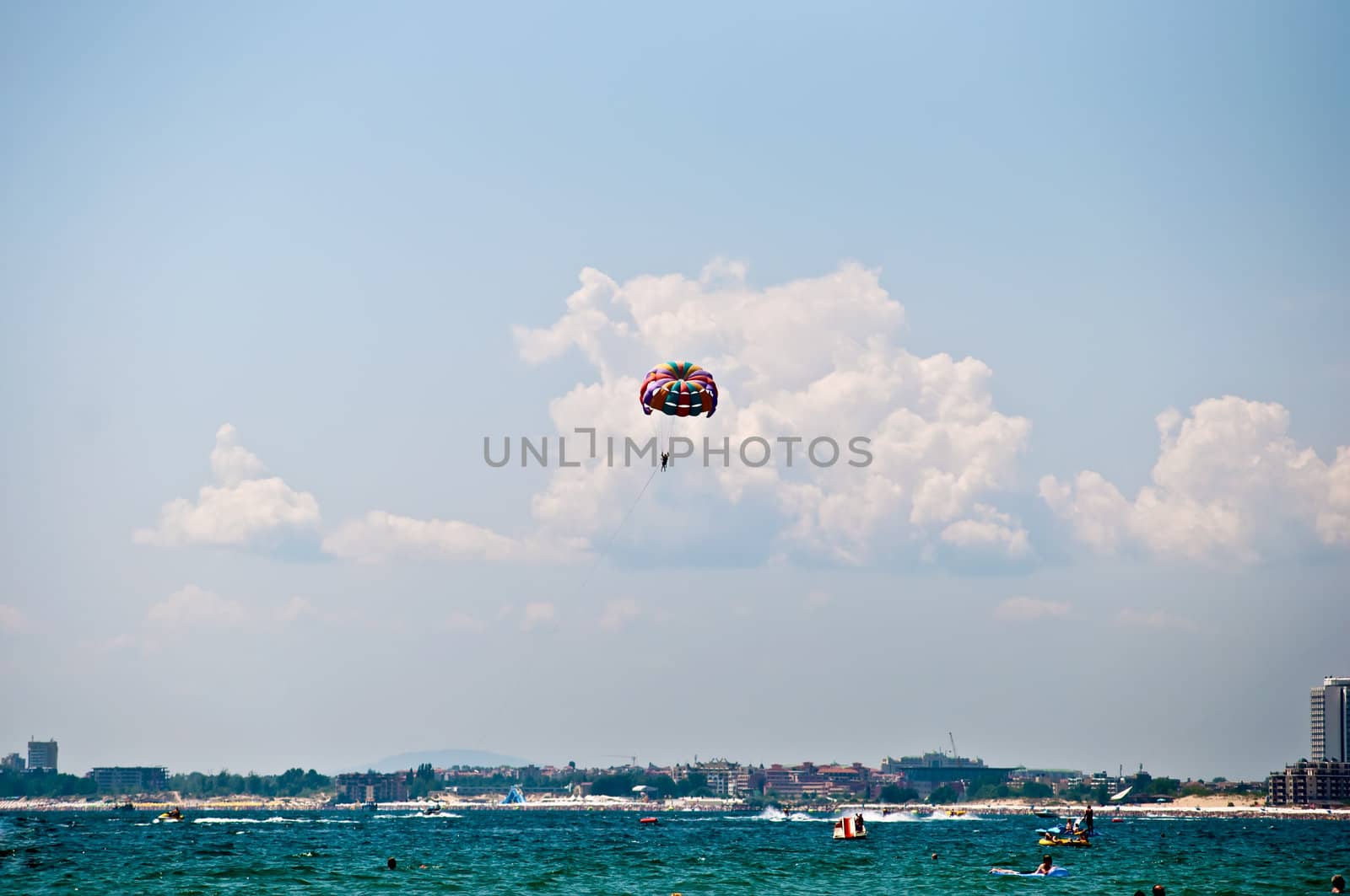 Colorful hang glider in sky over blue sea .