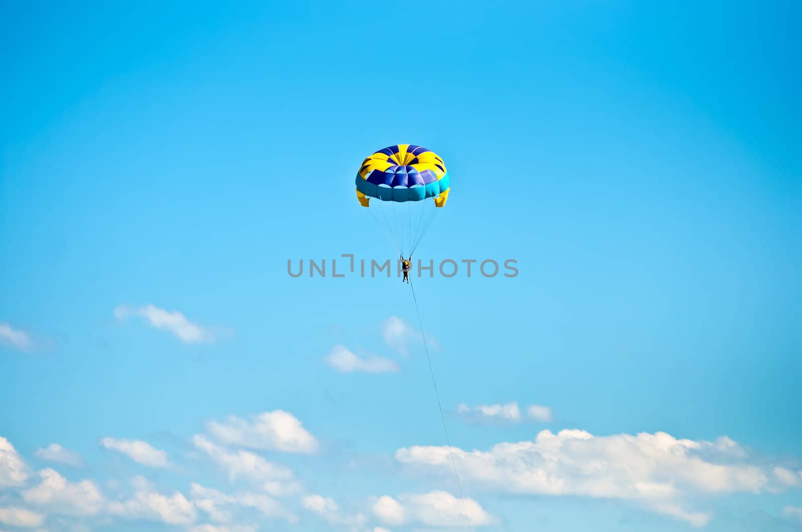 Colorful hang glider in sky over blue sea .