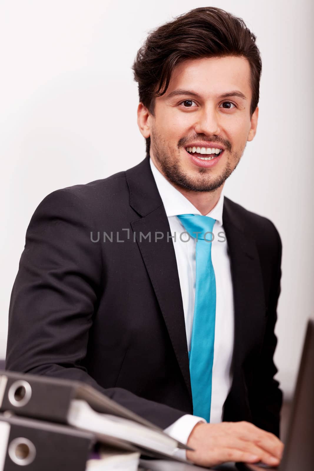 young businessman smiling at office with folders on desk