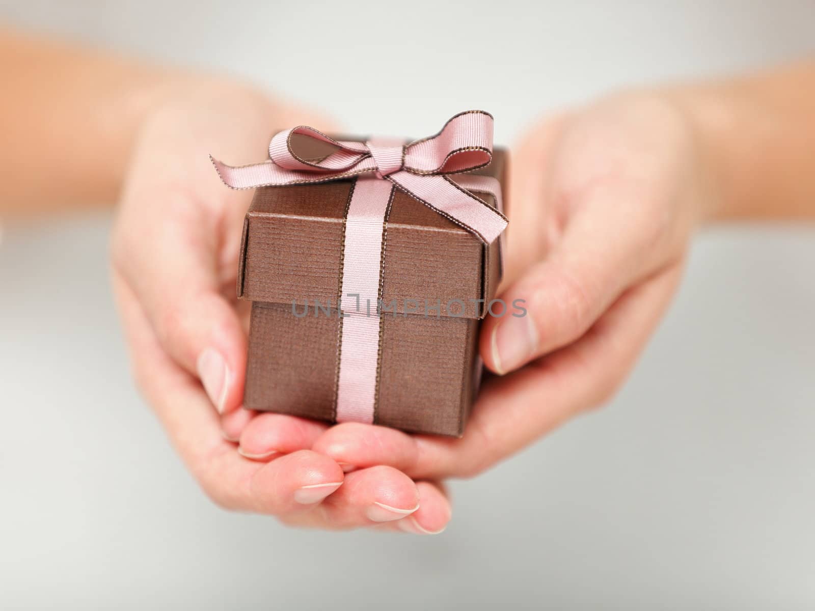 Present / gift. Close up of hands holding small gift with ribbon.