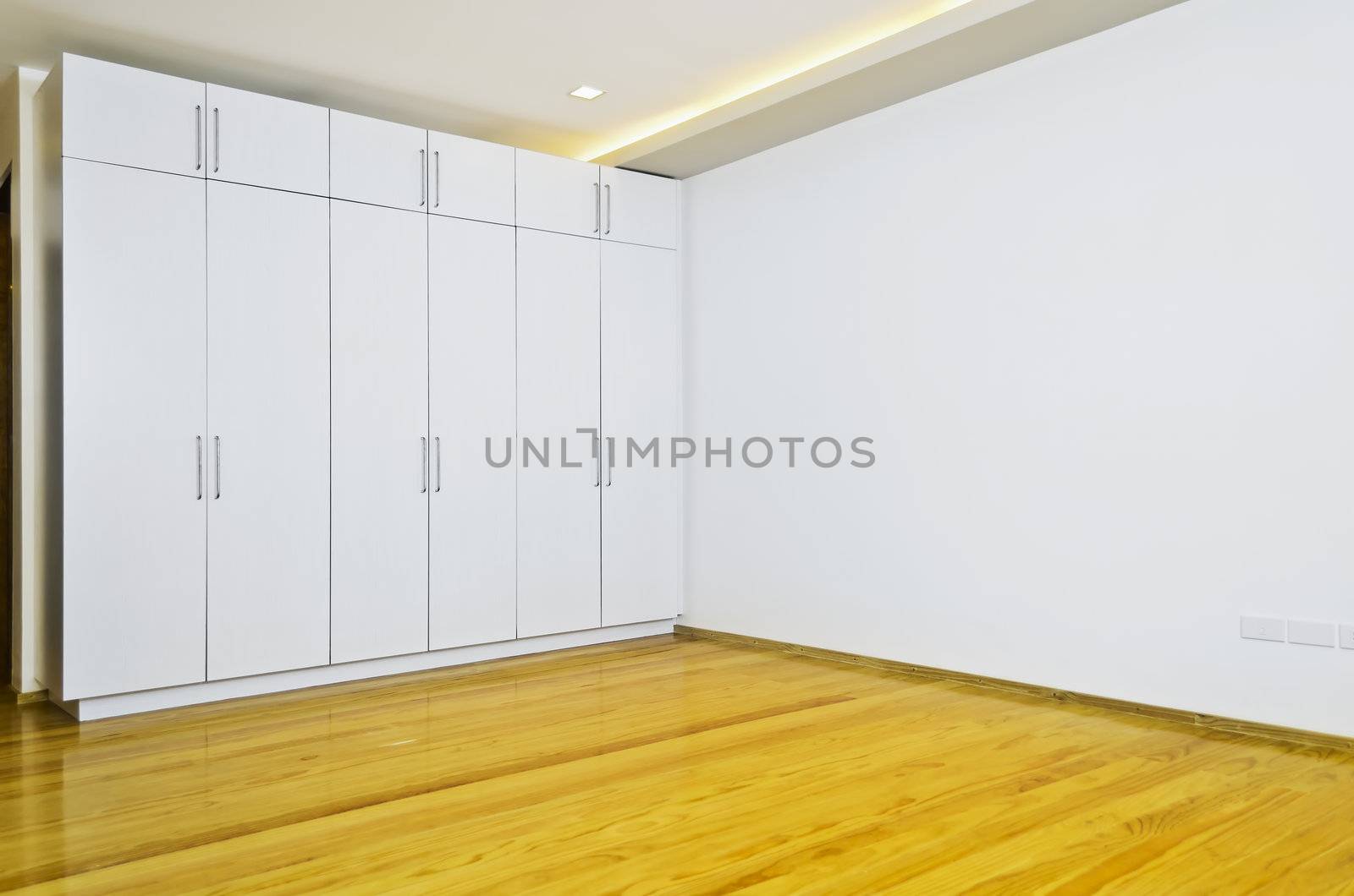 Newly built and painted room with wooden flooring and white cabinets