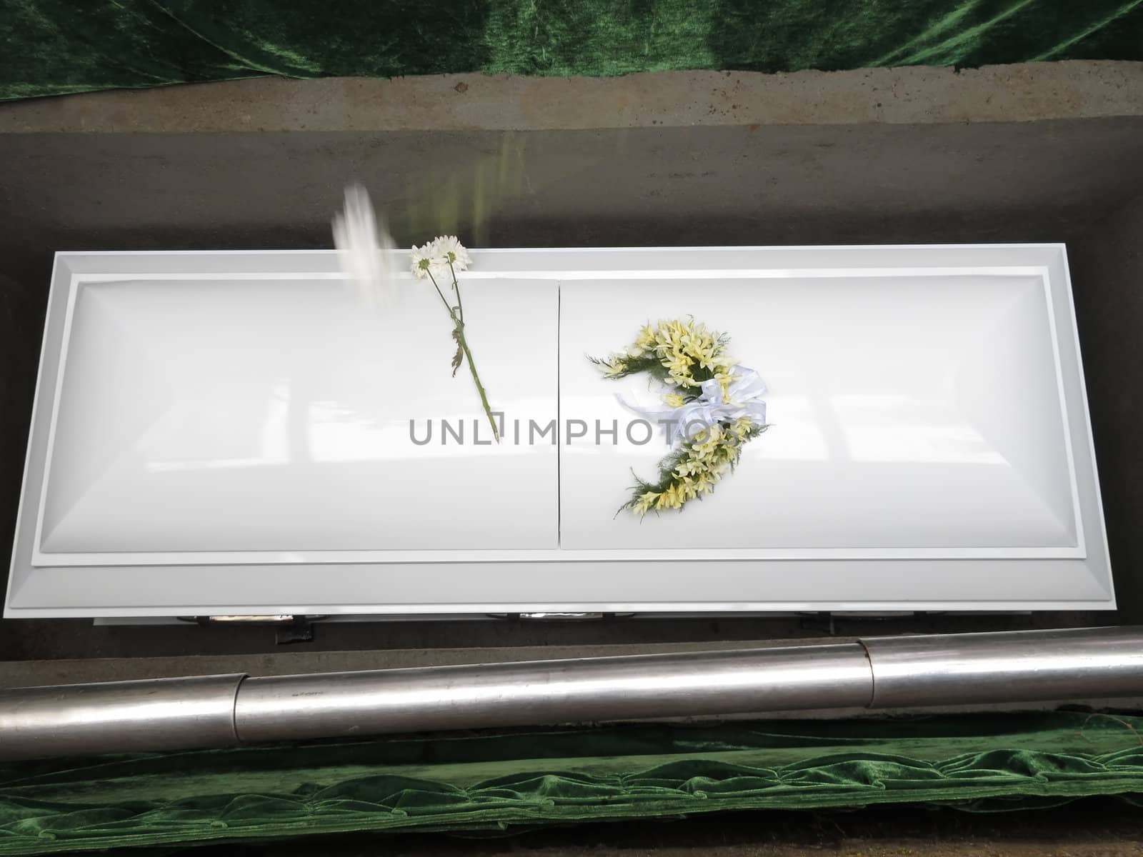 White coffin in grave during funeral