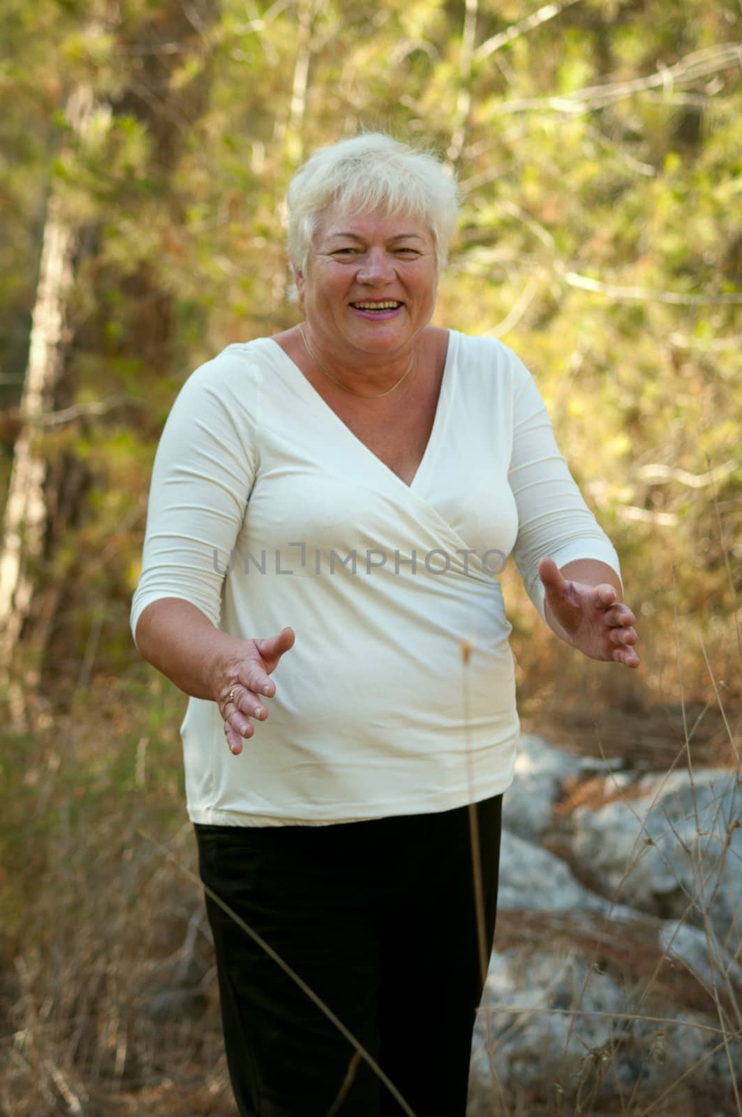 Smiling Senior woman exercising in leafy park .