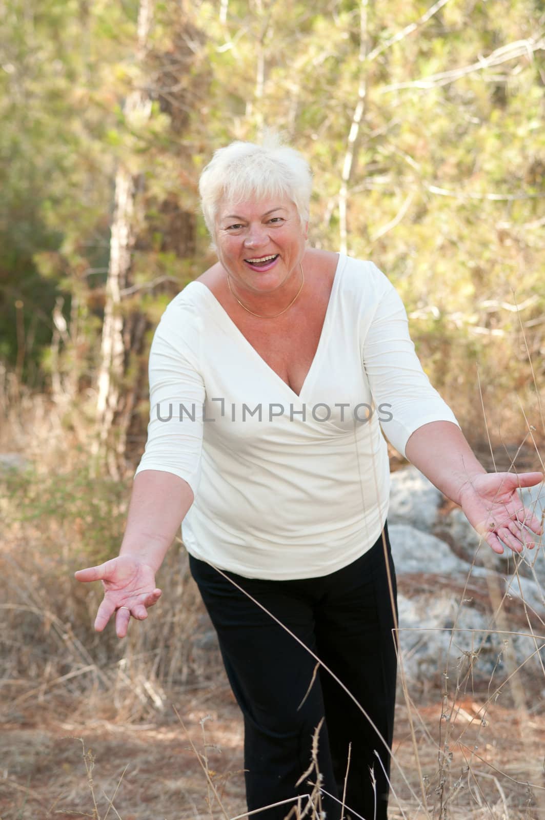 Smiling Senior woman exercising in leafy park .