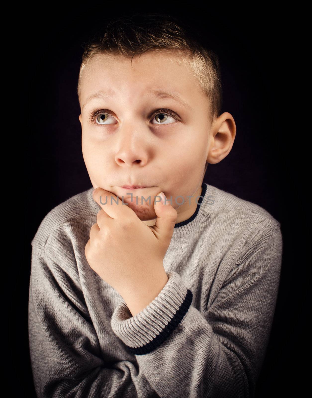 Boy with hand on chin and looking up trying to solve a problem