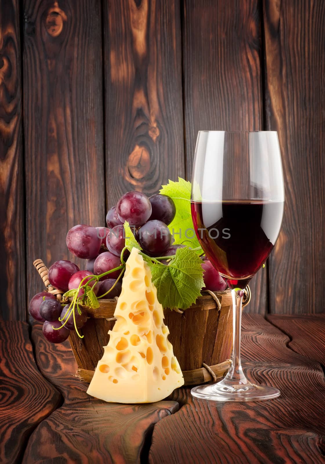 Wine glass and cheese in a basket on a wooden background