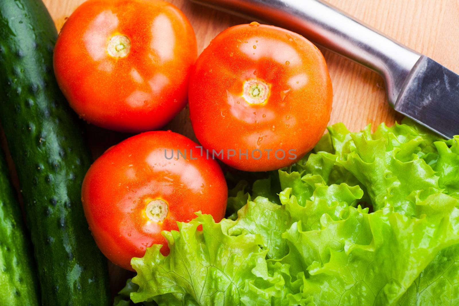 Vegetables (tomato, cucumber, salad) on a wooden table
