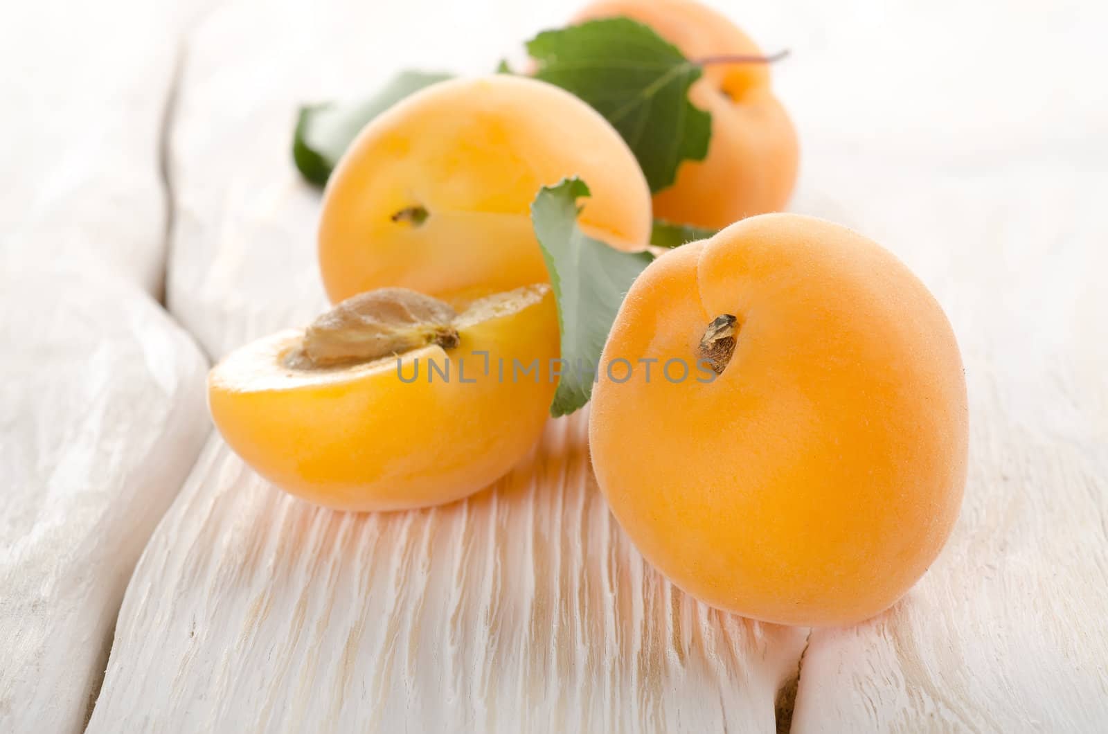 Ripe apricots on a white wooden background