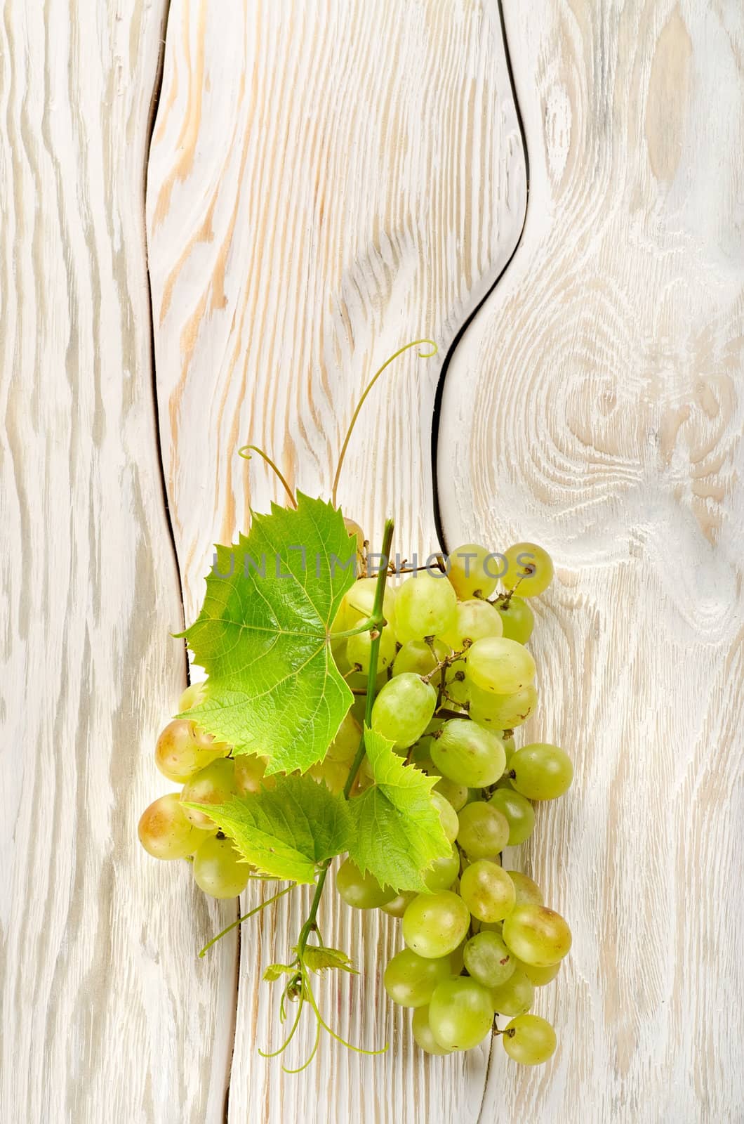 Green grapes on a white wooden background