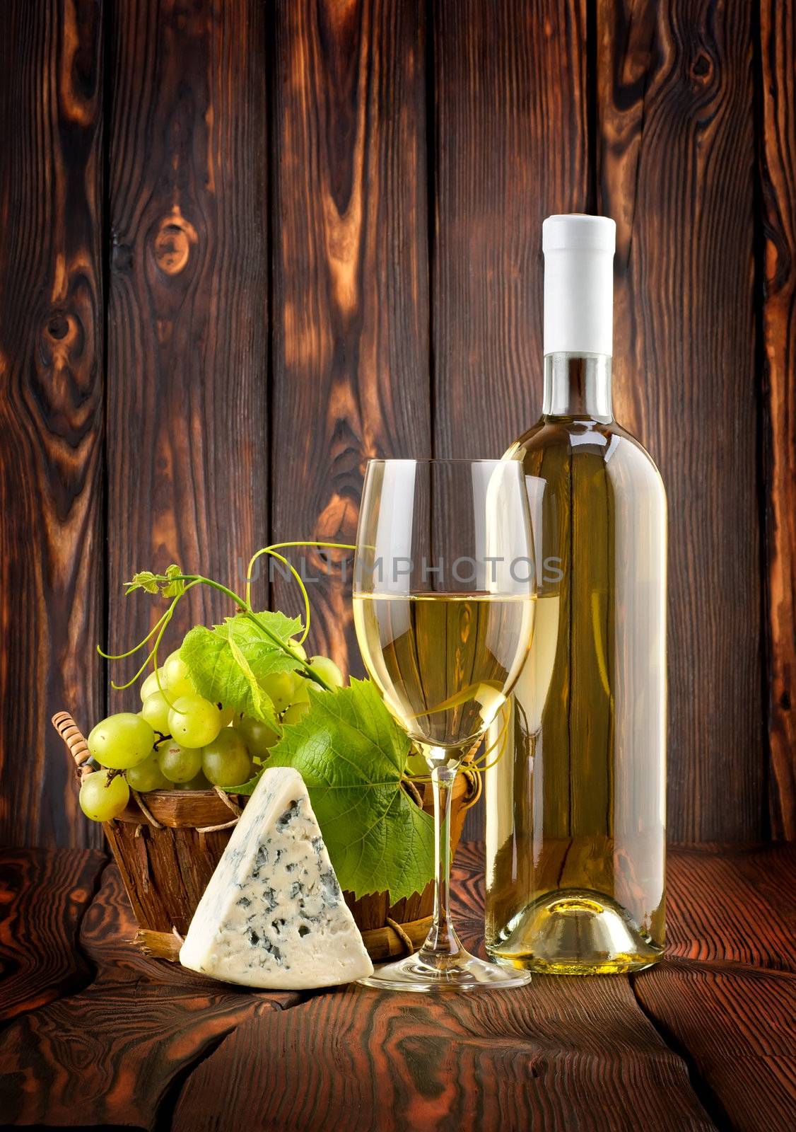 White wine with grapes and blue cheese on a wooden background