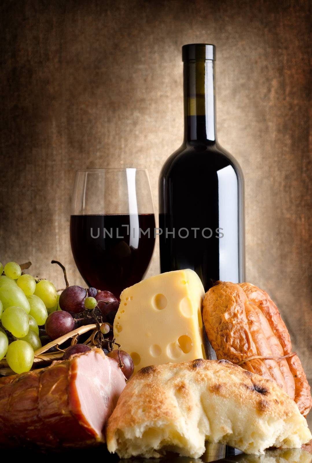 Wine, cheese, grapes and sausage on an old canvas