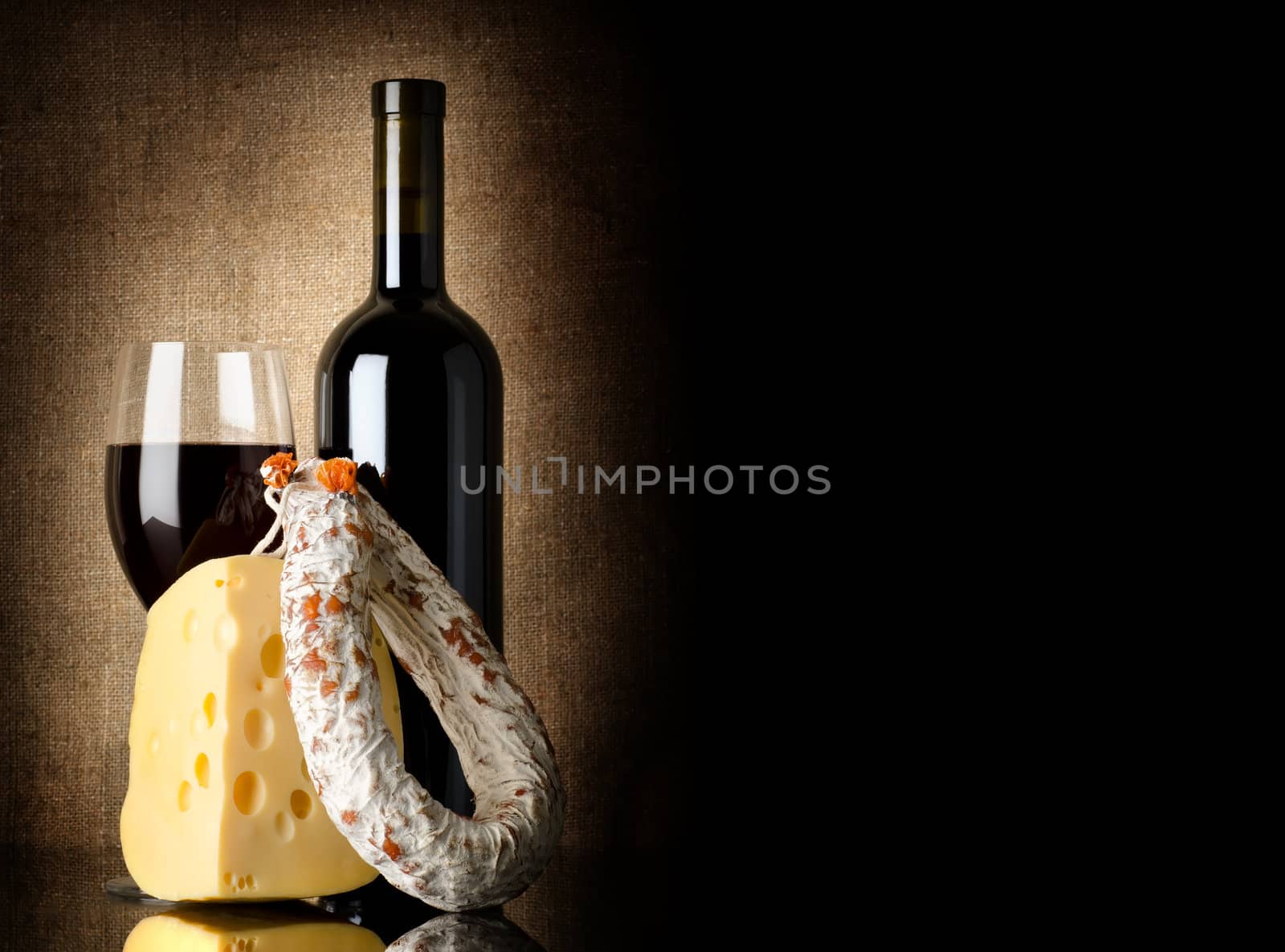 Wine, cheese and salami on a background of old canvas