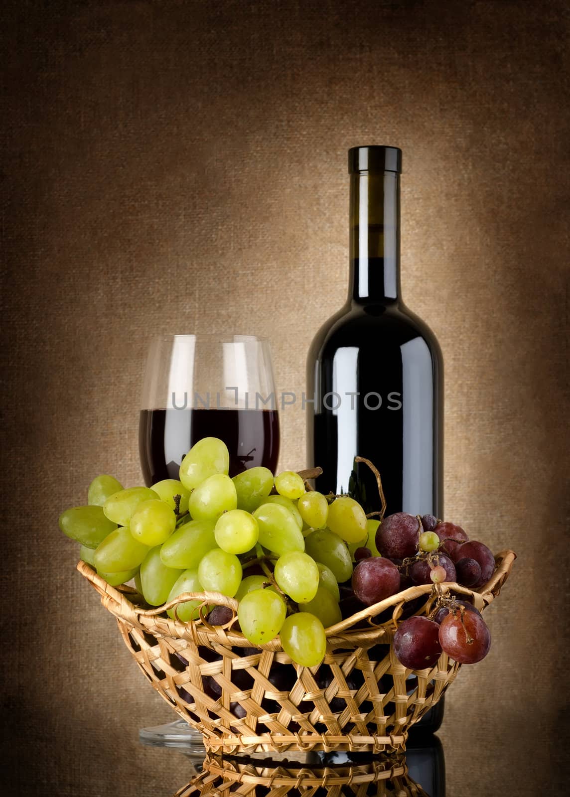 Bottle of red wine and grapes on a background canvas