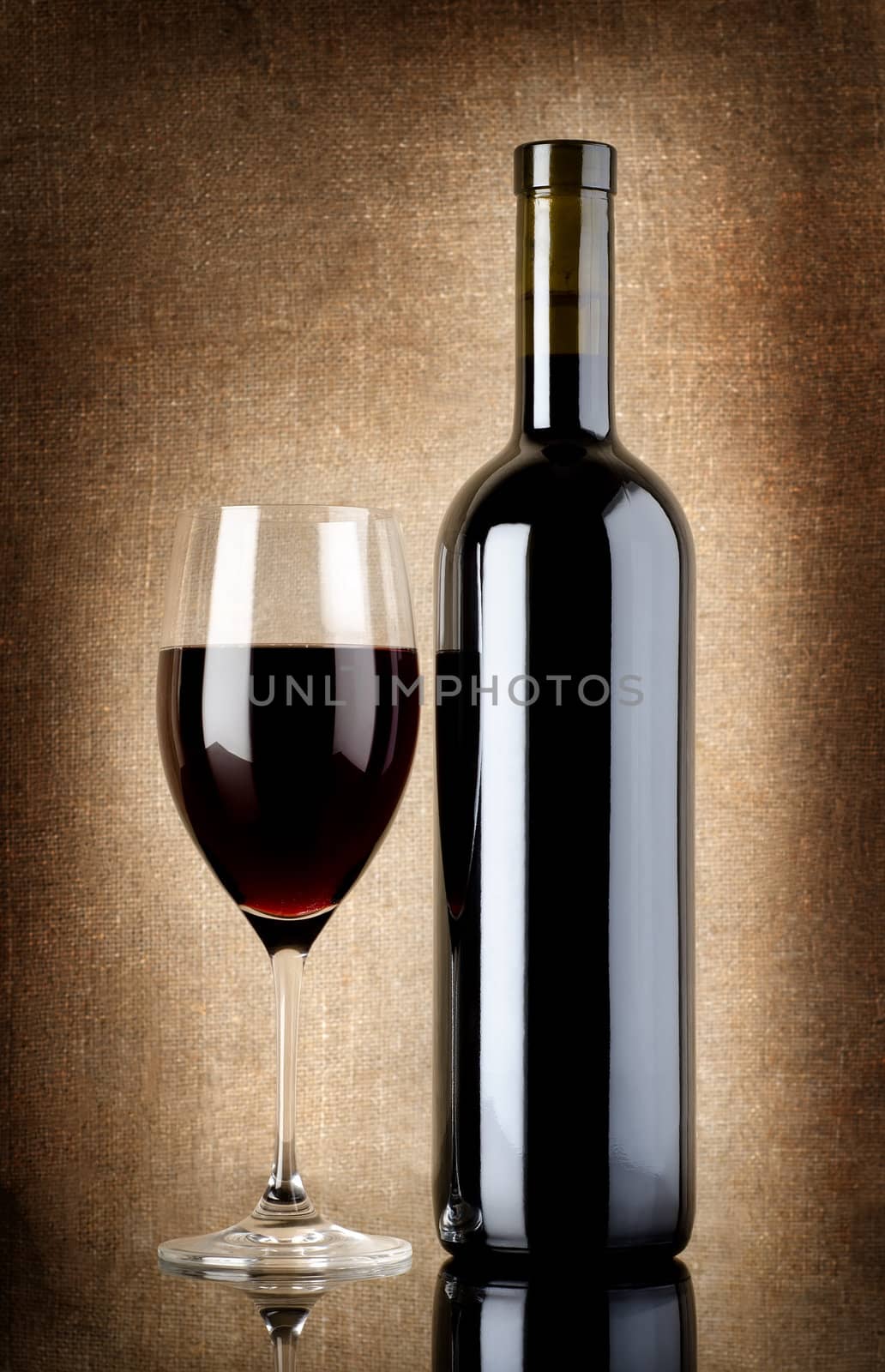 Wine bottle and wineglass on a background of old canvas