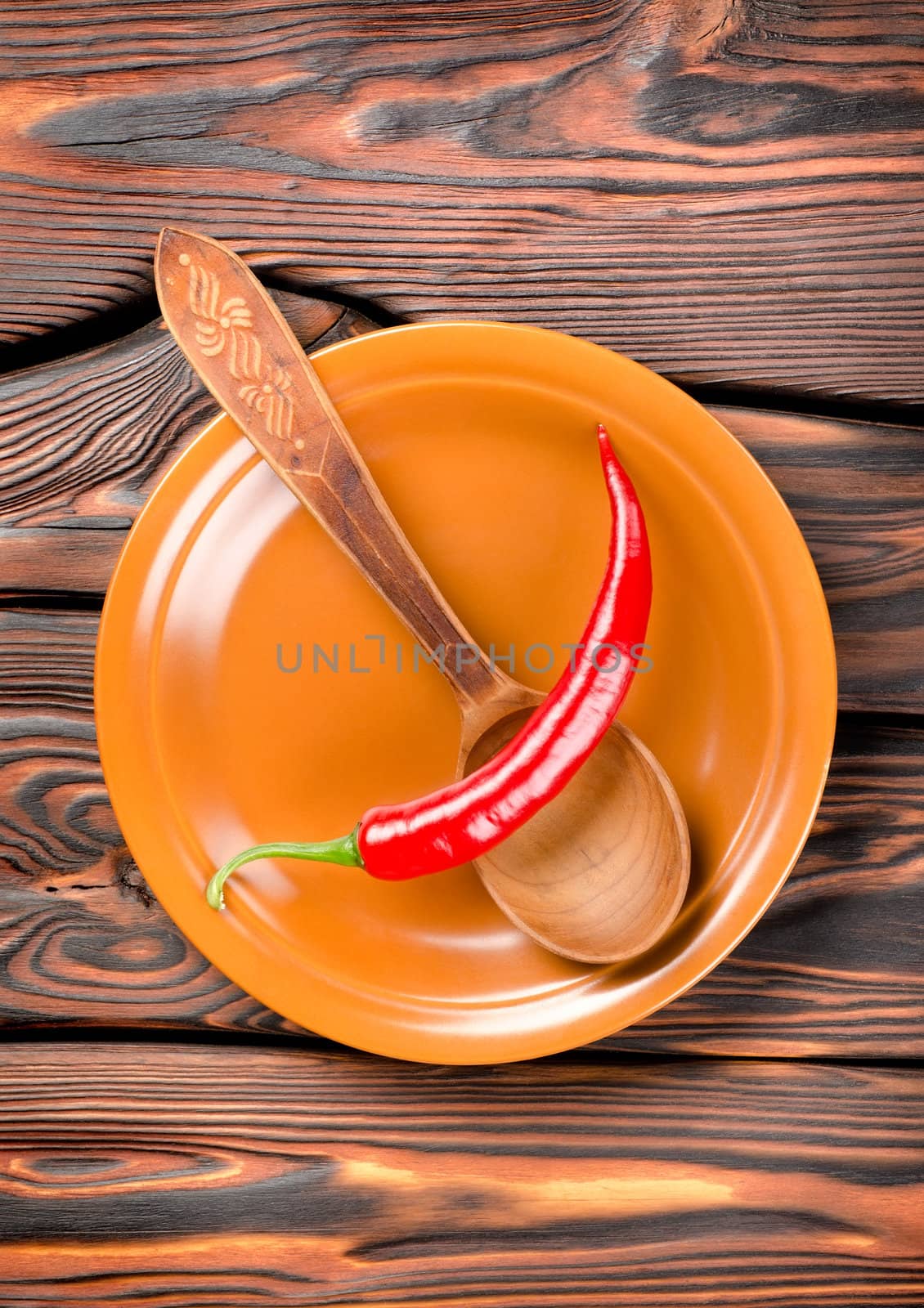 Pepper in a plate and spoon on a wooden background