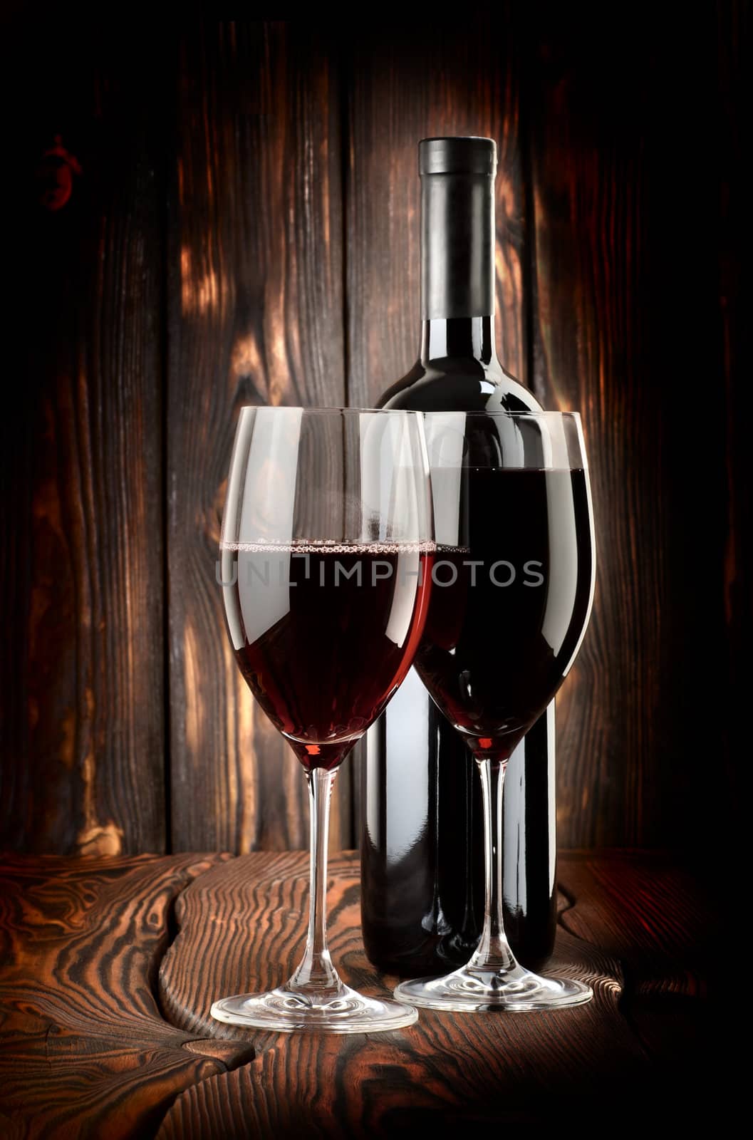 Two glasses of wine and wine bottle on a wooden background