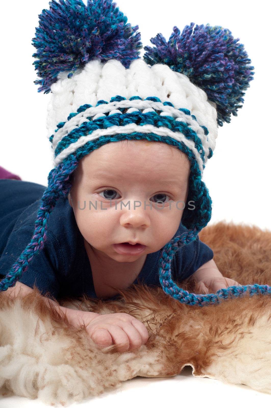 Little baby in pom-pon hat lying on fur