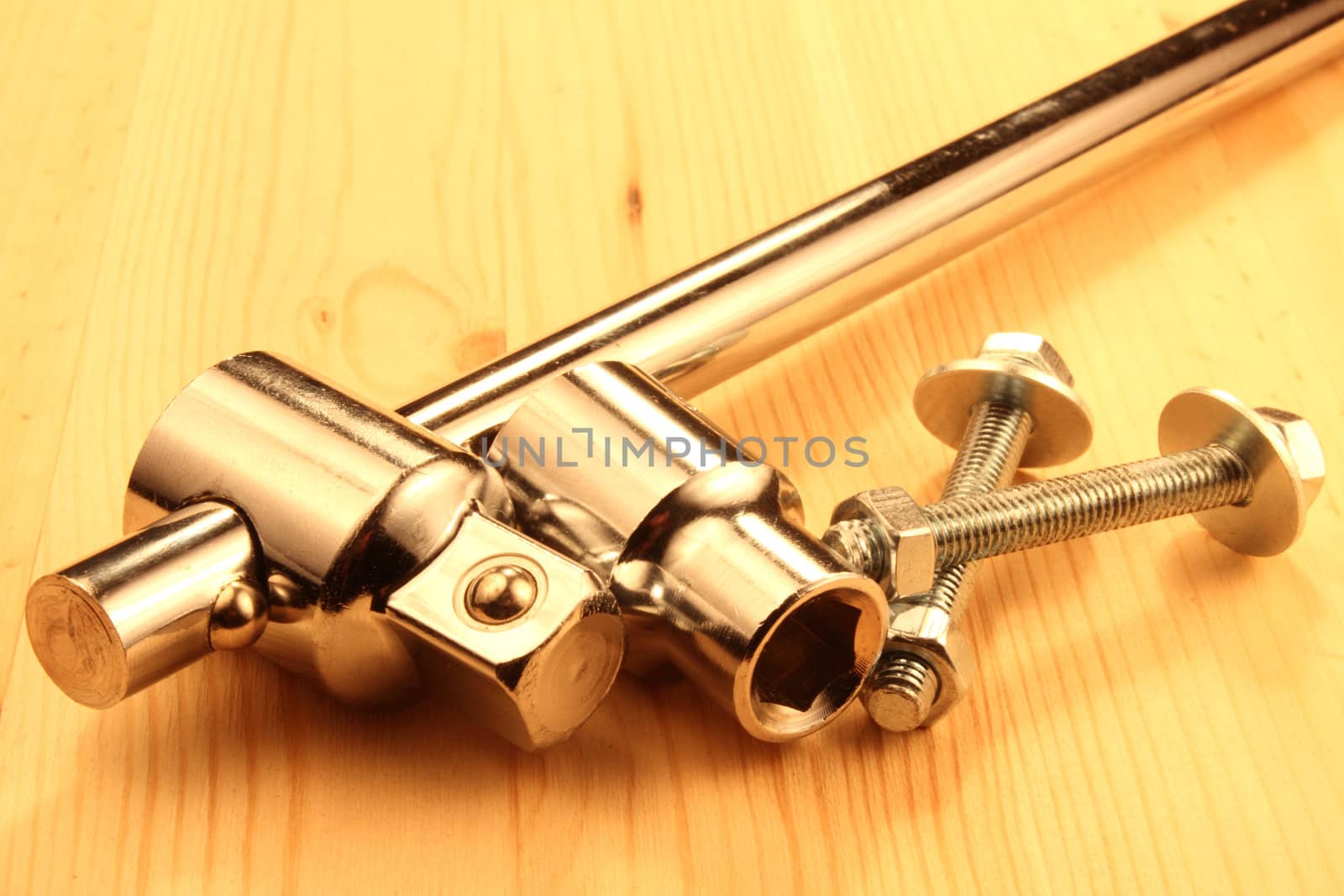 Wrench with sockets and two screws with nuts and plated on wood table.