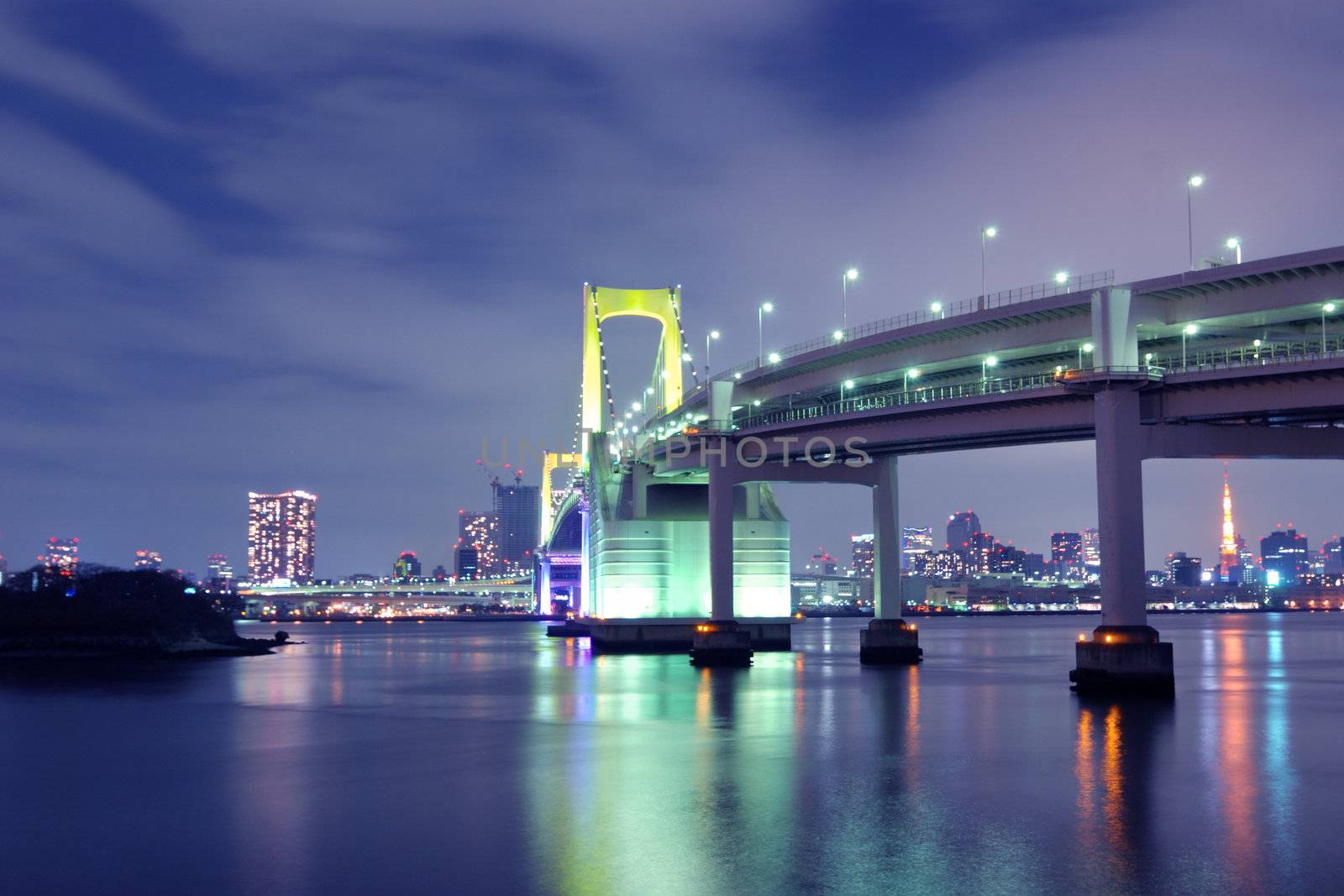 one of famous Tokyo landmarks, Tokyo Rainbow suspension bridge supports over night waters with scenic colourful illumination