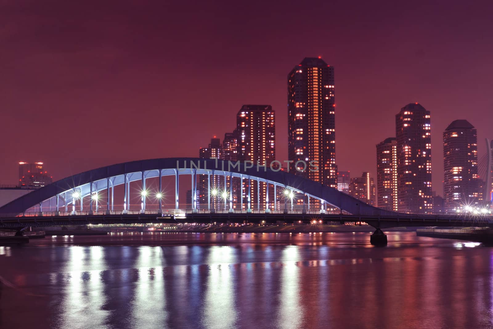 Tokyo skyline view over Sumida river night waters with metallic Eitai bridge and Tsukishima residential district