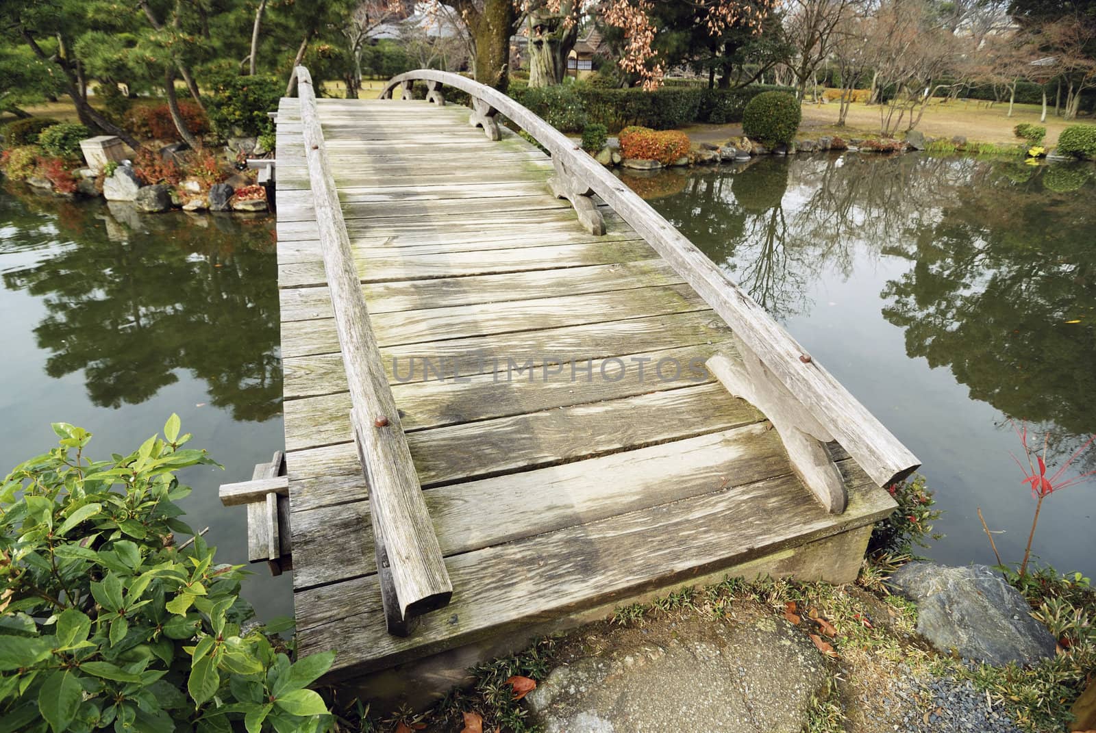  scenic wooden bridge in Japanese garden at early autumn; focus on front side