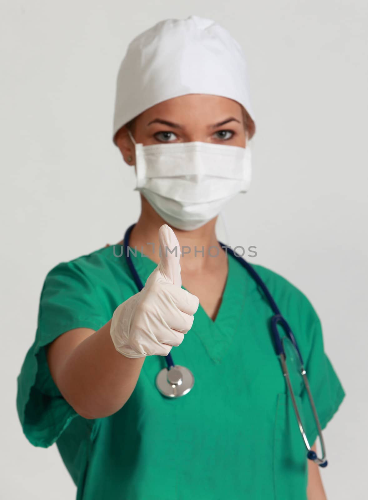 Portrait of a young woman doctor with her right thumb up, isolated against a white background.Selective focus on the thumb.
