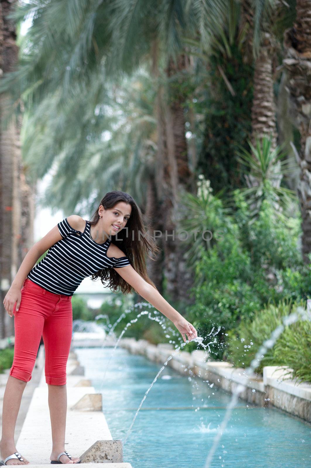 Happy young  a girl near the fountain.