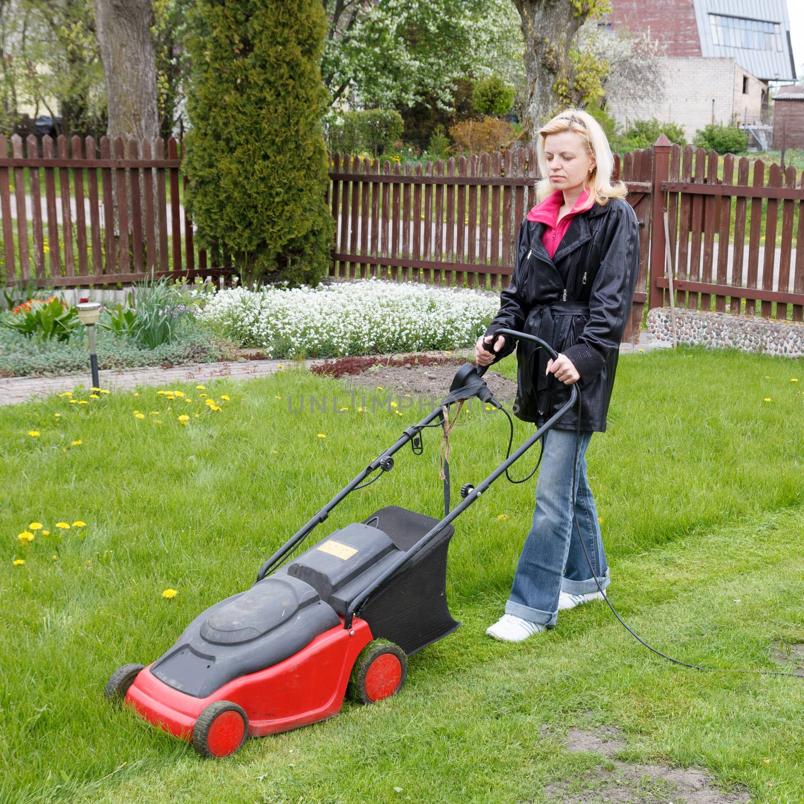woman mowing grass with an electric lawn mower