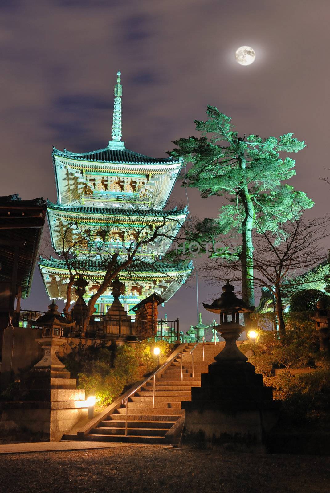 Kiyomizudera pagoda in Kyoto by night under moonlight and city illumination with entrance stairs