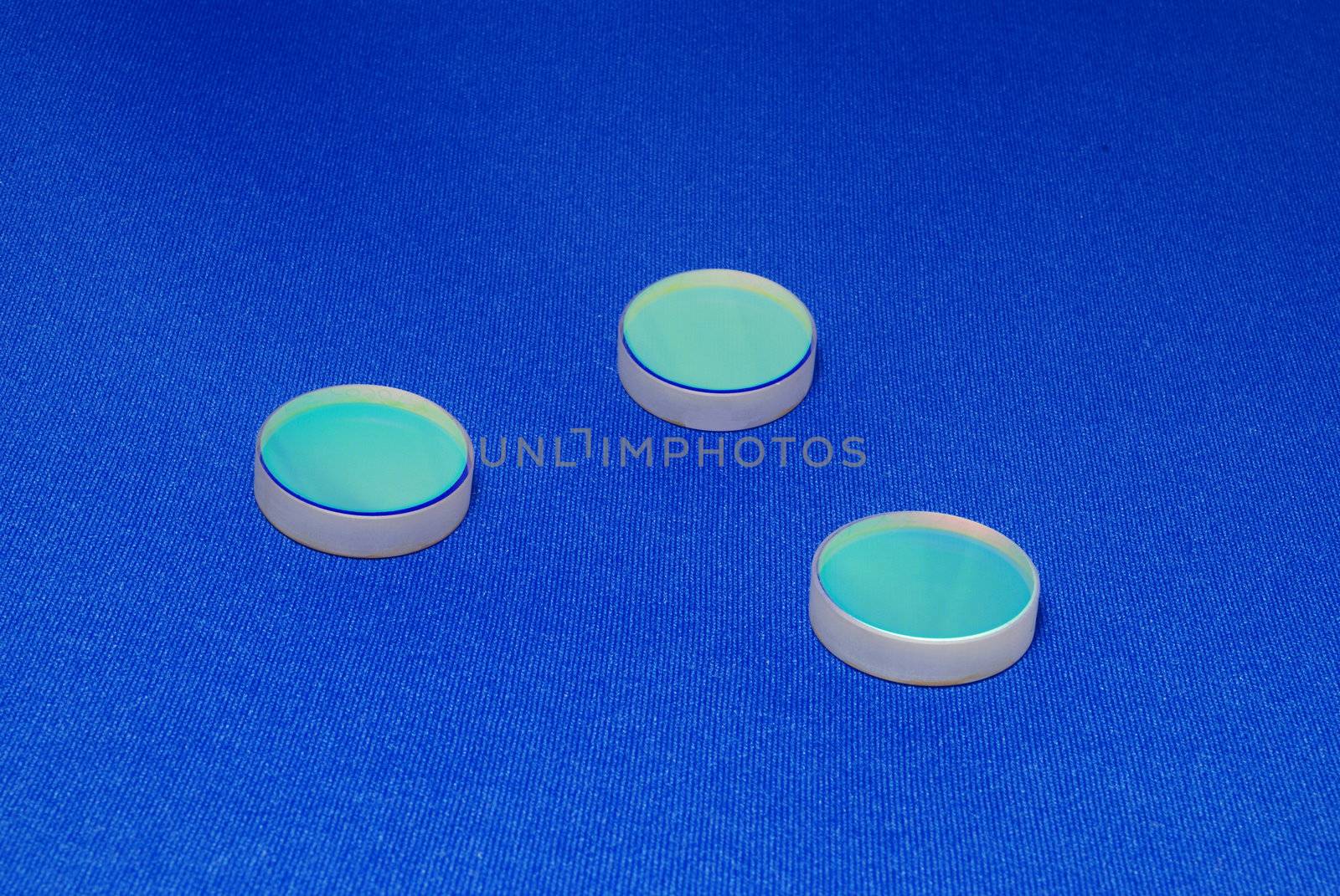  laser industry optical components ; flat thick mirrors with special reflection coating used in Laboratory Science and in Laser Manufacture on the blue canvas background