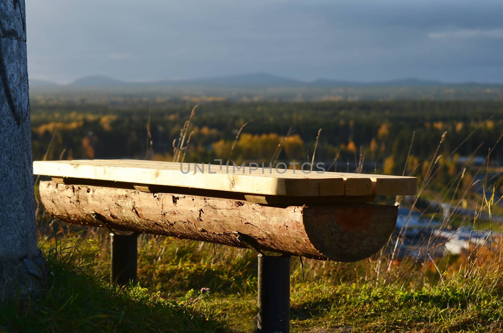 A bench of wood at a lookout with view of a woodland in northern Sweden